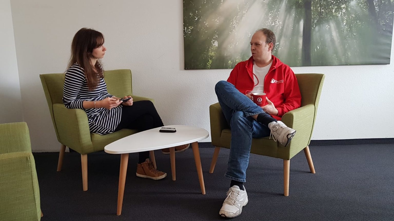 Zwei Personen im Gespräch in einem modernen Büro, symbolisch für den Austausch über Dokumentenmanagement und digitale Archivierung.