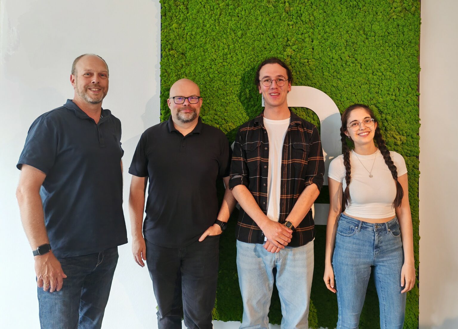 Team von Amagno, einem Anbieter für Dokumentenmanagement und digitale Archivierung, vor einer begrünten Wand.